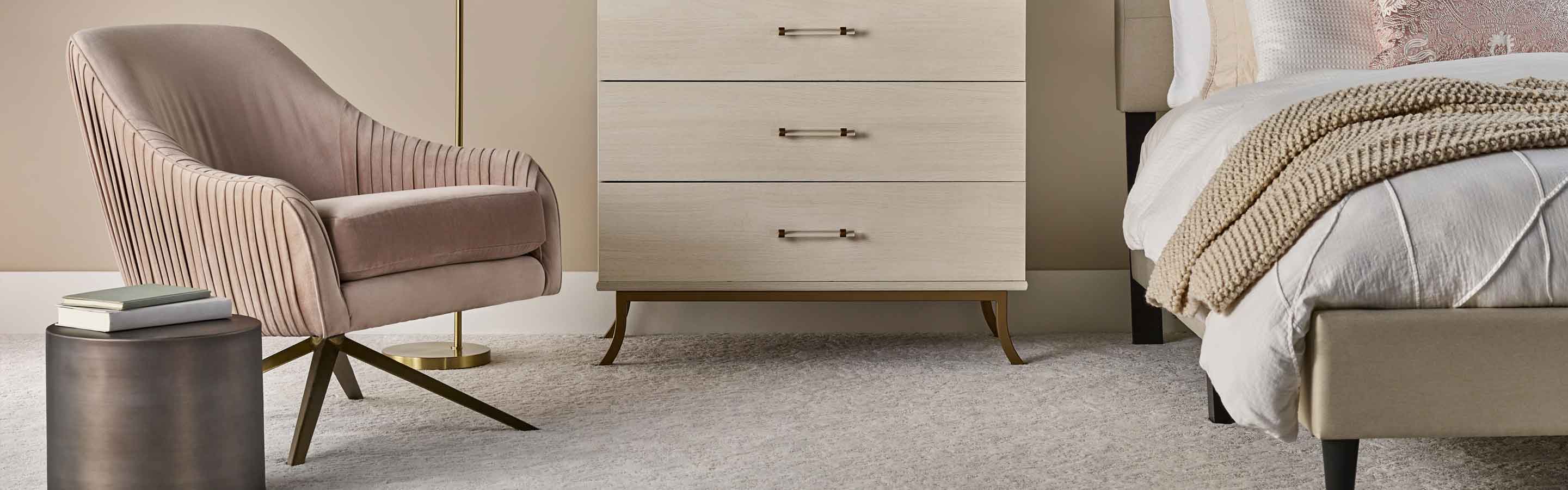 textured beige carpet in modern bedroom with blush pink accents, pink chair and layered bedding