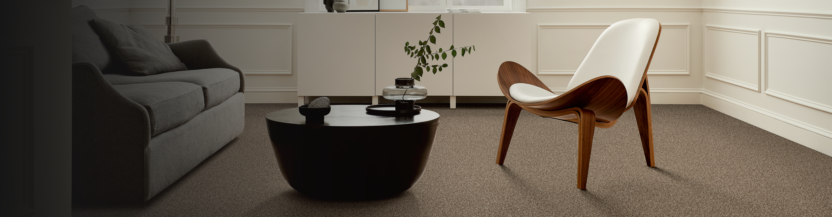 beige carpet in contemporary living room with black coffee table, abstract art and white modern chair