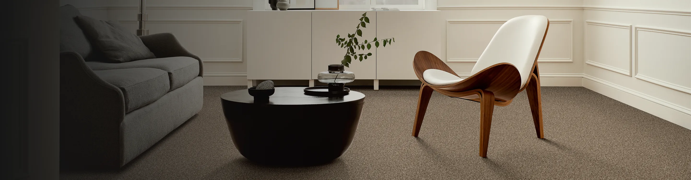 beige carpet in contemporary living room with black coffee table, abstract art and white modern chair